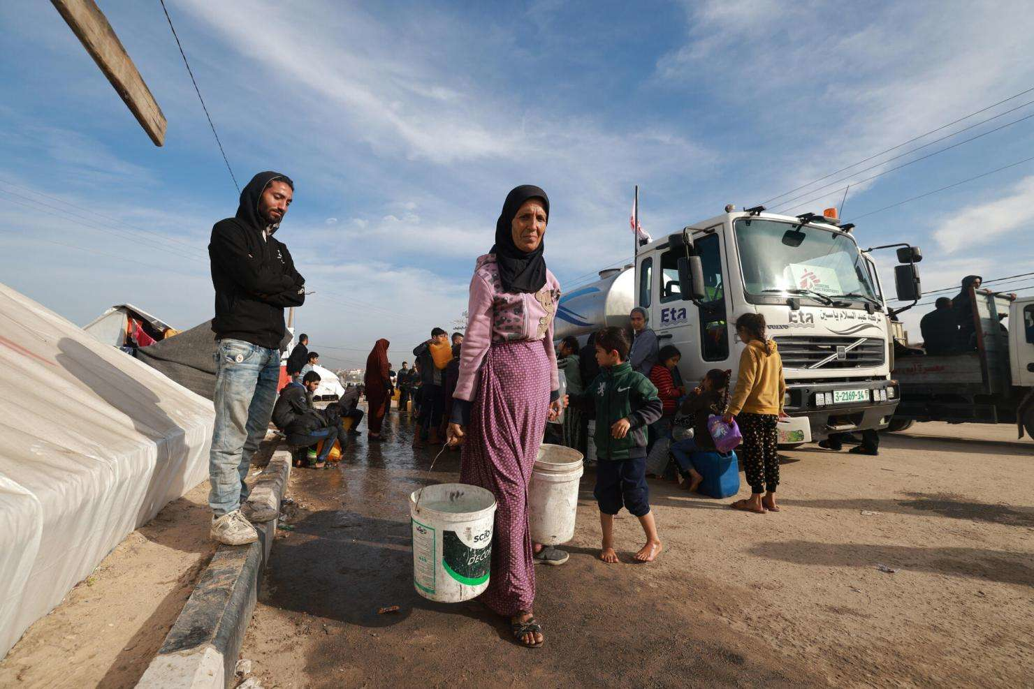 People in Gaza collecting water from a humanitarian water tanker amid the water crisis