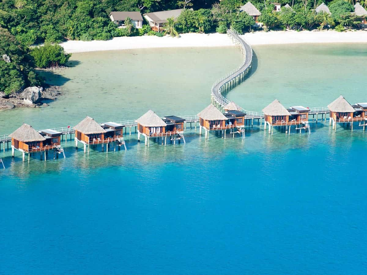 Luxury overwater bungalows in Fiji set above crystal clear water with direct access to a lush island beach