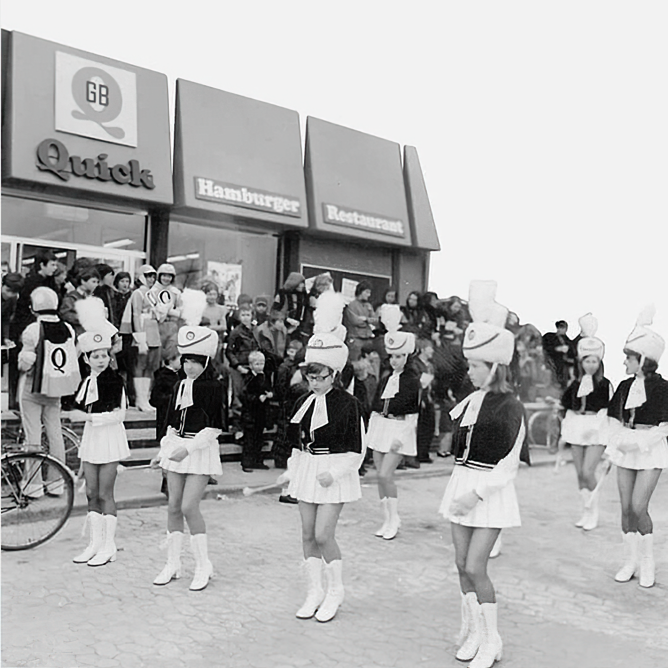 1971 opening event at the first Quick restaurant in Schoten, Belgium, featuring majorettes and a crowd gathered outside