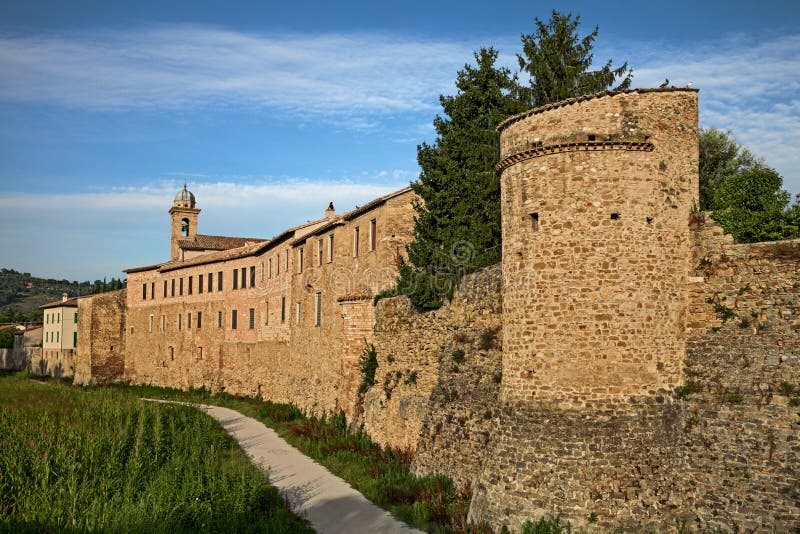 Medieval city walls and tower in Umbrian town, showcasing historical stone architecture and religious heritage