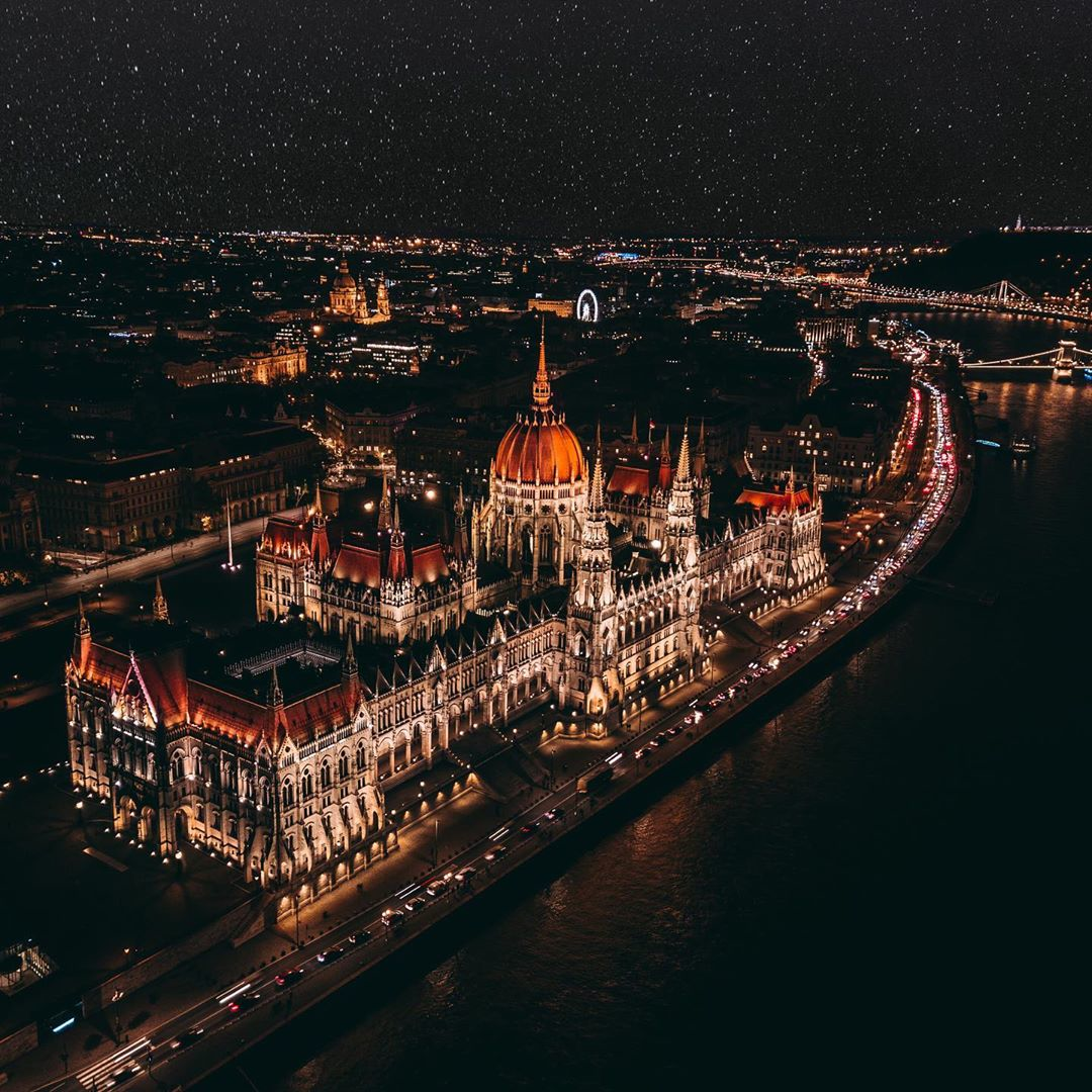 Vista aérea nocturna del Parlamento húngaro iluminado junto al Danubio