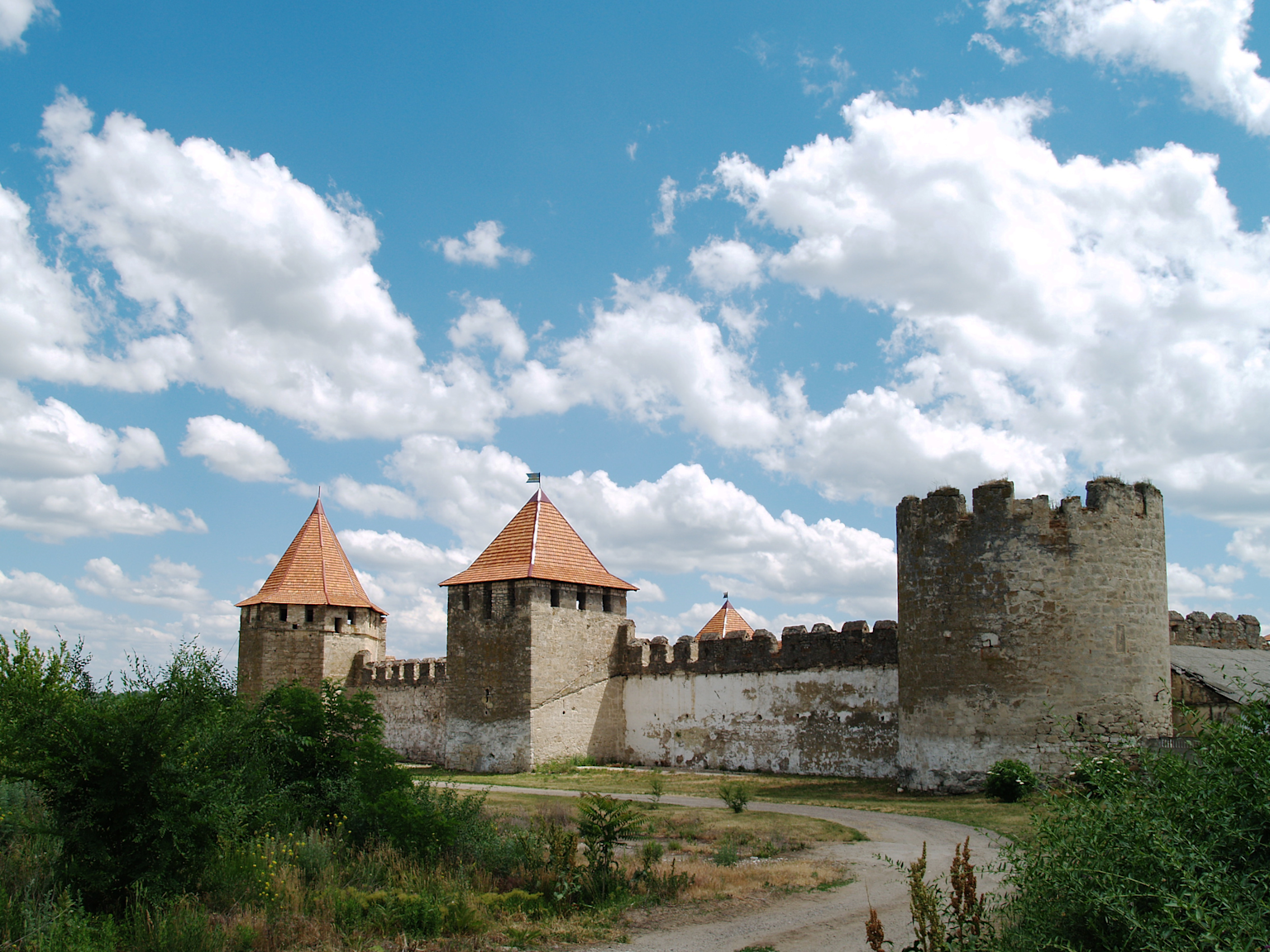 Bender Fortress in Transnistria features historic stone walls and distinctive conical-roofed towers under a bright blue sky