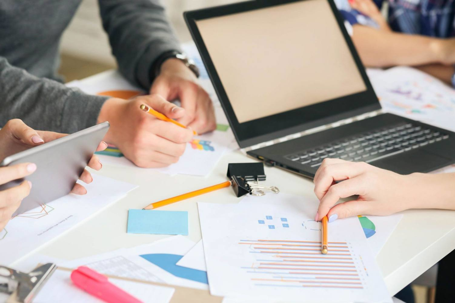 Collaborative research workspace with charts, laptop, and tablet