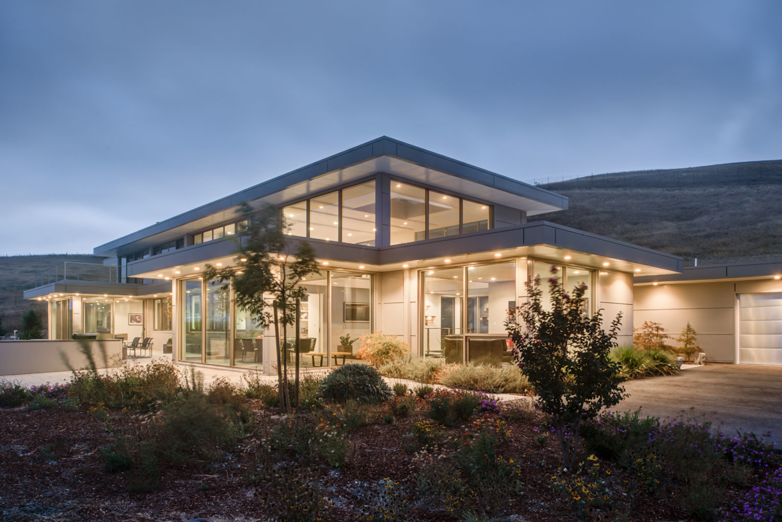 Modern prefabricated steel and glass home with large windows and minimalist design surrounded by natural landscape