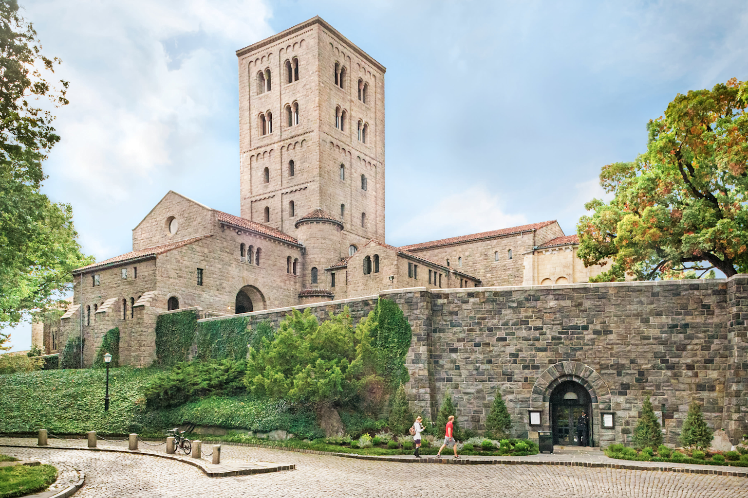 Exterior view of The Met Cloisters museum building in Fort Tryon Park, showcasing its medieval stone architecture and surrounding greenery