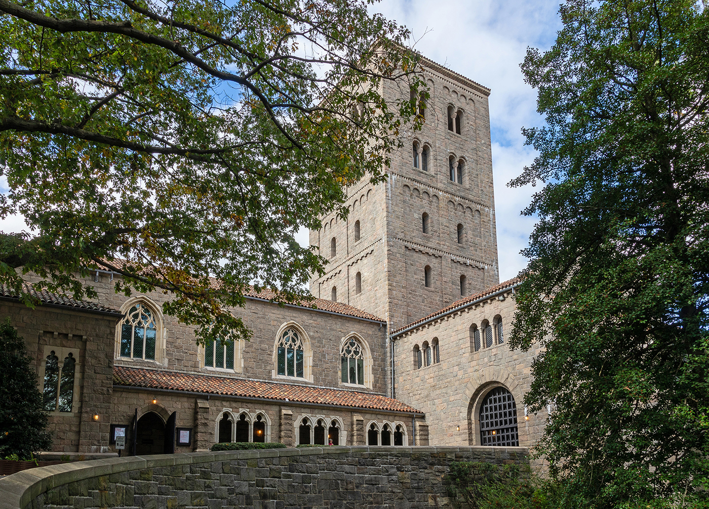 Exterior view of The Met Cloisters museum in Fort Tryon Park, showcasing its medieval-style stone architecture and tower