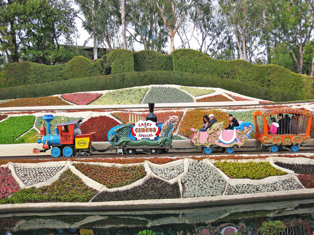 Casey Jr. Circus Train with colorful animal cage cars traveling through the garden at Disneyland's Fantasyland.