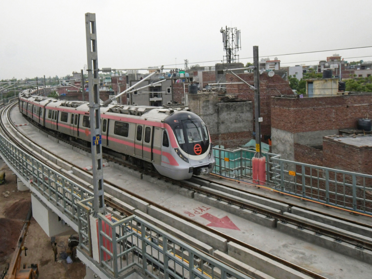 Driverless Delhi Metro train operating on elevated tracks of the Pink Line amid urban surroundings