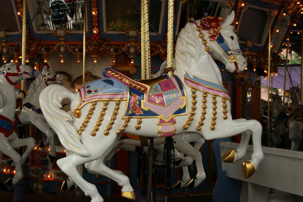 Jingles, the lead white carousel horse at King Arthur Carrousel in Disneyland's Fantasyland, decorated with golden bells and a 50th anniversary saddle.