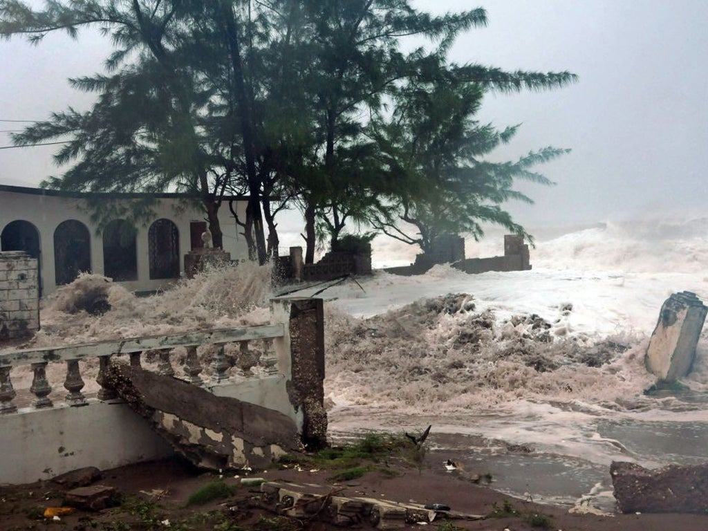 Severe coastal flooding and damage caused by a hurricane near Kingston, Jamaica, showing smashed structures and crashing waves