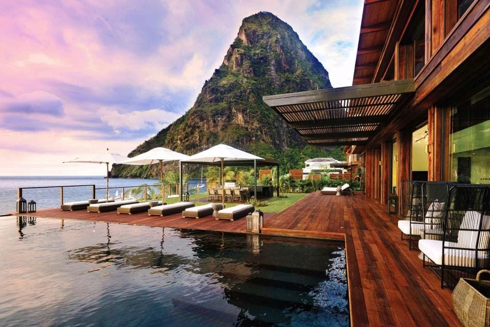 Luxury tropical beach resort with infinity pool and mountain backdrop in the Caribbean