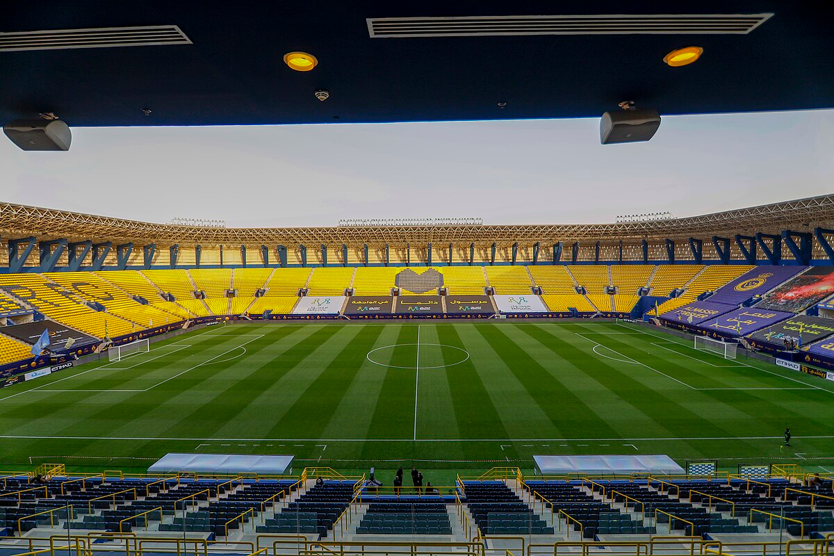 Inside view of King Saud University Stadium, home of Al-Nassr, showcasing the yellow seating and pristine football field.