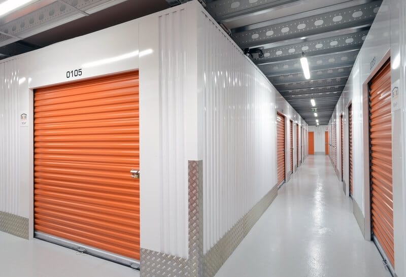 Modern self-storage facility corridor with bright orange storage units available for rent